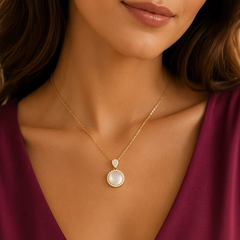Elegant EVAH JEWELS 18K gold-plated moonstone halo pendant necklace for women, featuring a round luminous moonstone-style pendant surrounded by sparkling CZ stones, worn by a female model in a burgundy dress. Premium gold-plated fashion jewellery for women, ideal for everyday wear, parties, weddings and gifting.
