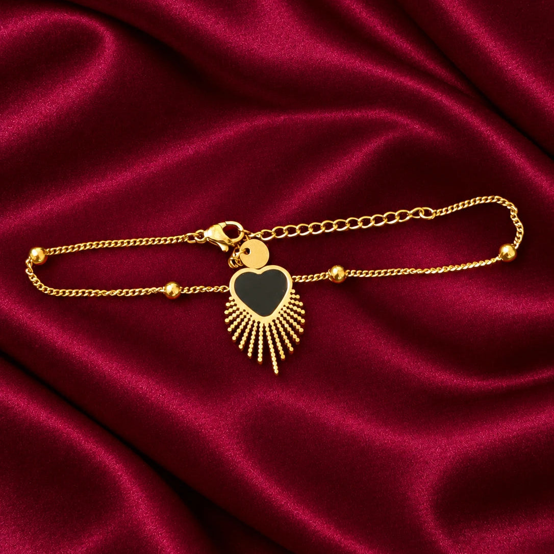 Add a touch of modern elegance to your jewellery collection with the EVAH JEWELS Gold Tone Black Heart Charm Bracelet for Women, a beautifully designed fashion jewellery accessory featuring a delicate gold-tone chain, polished round bead accents and a striking black heart-shaped centerpiece. The elegant heart charm is surrounded by a golden sunburst-inspired fringe design, creating a unique combination of romantic style and contemporary fashion. Featuring a lobster clasp and extension chain for an adjustabl