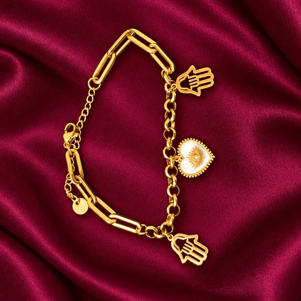 Gold Tone Hamsa Hand Charm Bracelet for Women with White Heart Evil Eye Charm, Stylish Chain Link Fashion Jewellery on Burgundy Satin.
