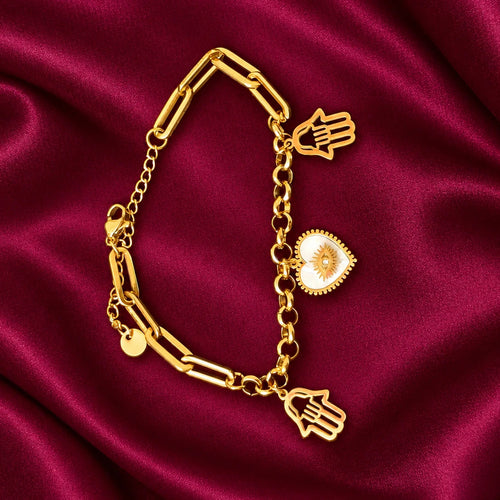 Gold Tone Hamsa Hand Charm Bracelet for Women with White Heart Evil Eye Charm, Stylish Chain Link Fashion Jewellery on Burgundy Satin.