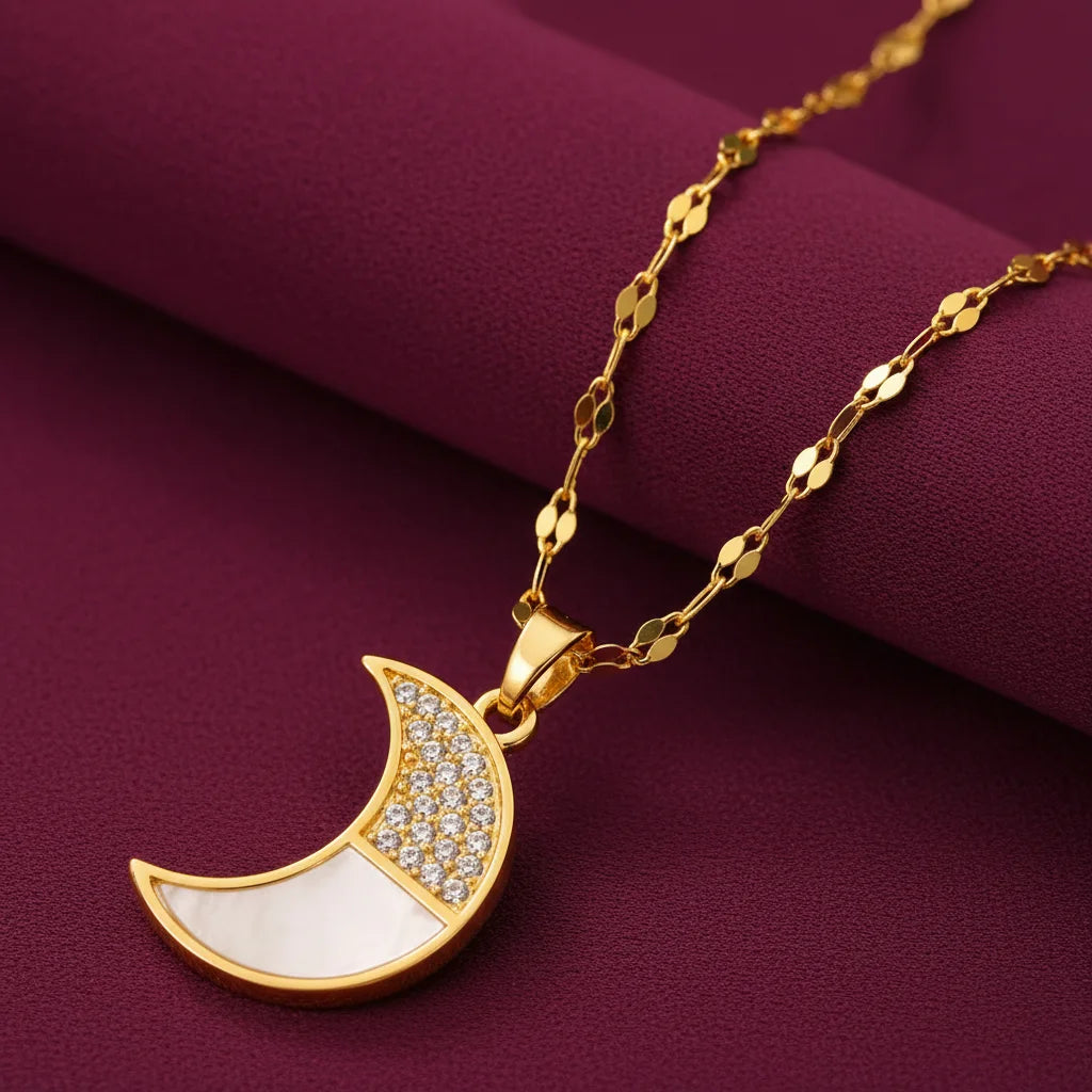 EVAH JEWELS gold-plated crescent moon mother of pearl pendant necklace for women featuring sparkling pavé-set crystals, elegant white mother of pearl inlay and a delicate gold-tone chain, displayed on luxurious burgundy fabric.