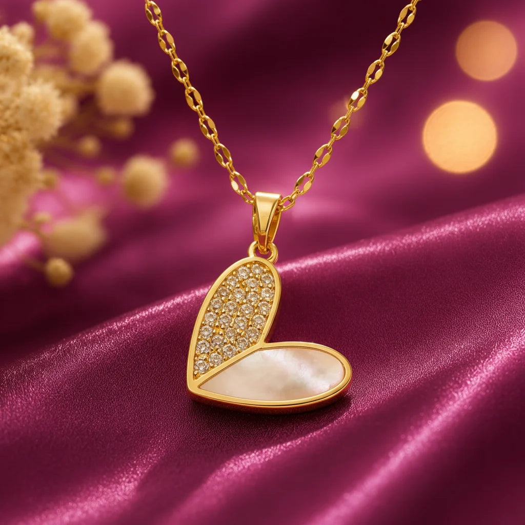 EVAH JEWELS gold-plated mother of pearl heart pendant necklace for women featuring a half pavé crystal-studded heart design, elegant white mother of pearl inlay and delicate gold-tone chain, displayed on luxurious pink satin.