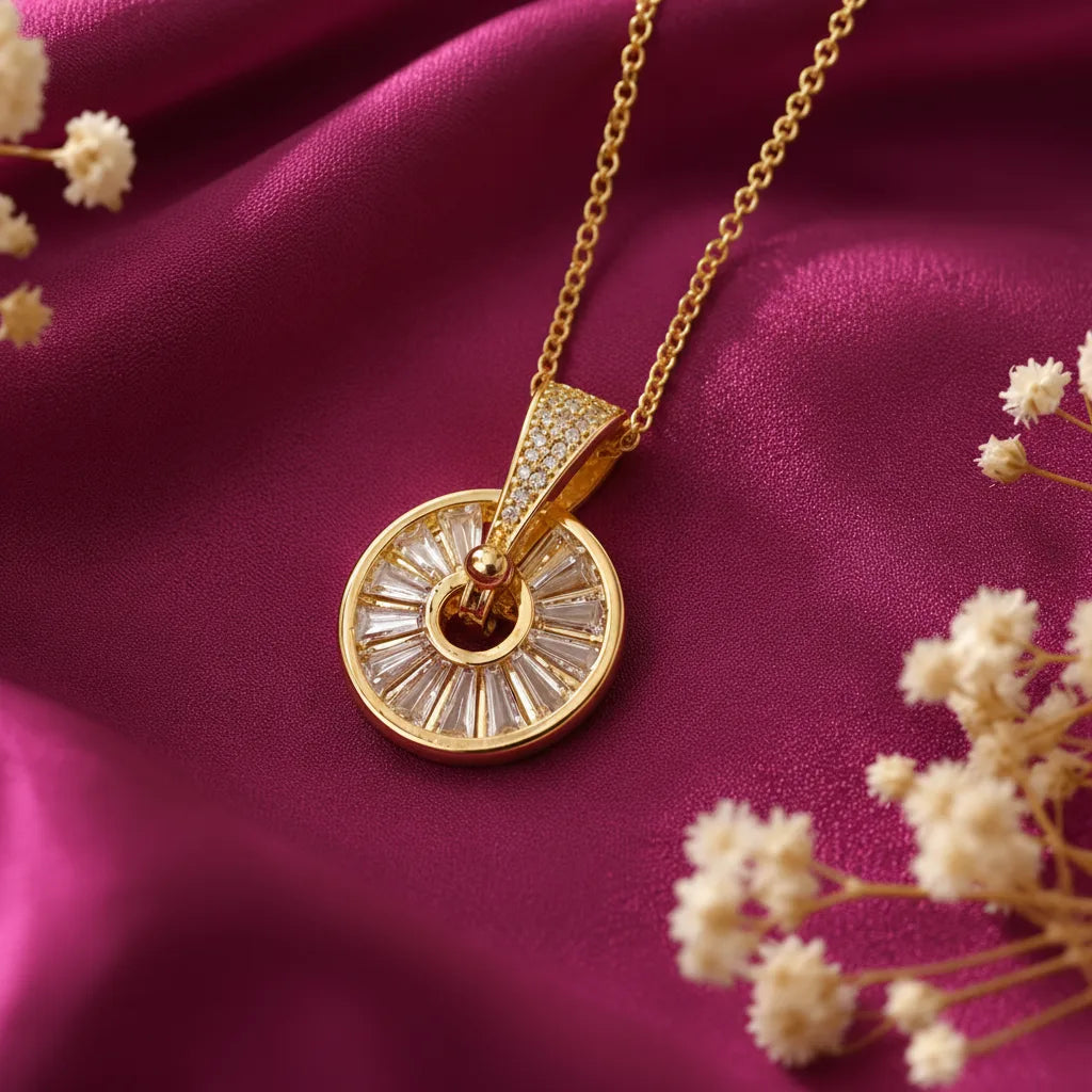 Elegant gold plated Sunburst Wheel Pendant Necklace for Women featuring a circular design with sparkling baguette-cut stones and a crystal-studded bail, displayed on luxurious pink satin fabric. Shop stylish anti-tarnish fashion jewellery online in India at EVAH JEWELS.