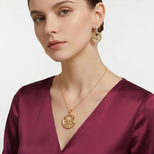 Woman wearing EVAH JEWELS gold-tone geometric circular pendant necklace with matching crystal-accented hoop drop earrings, featuring an intricate openwork starburst design.