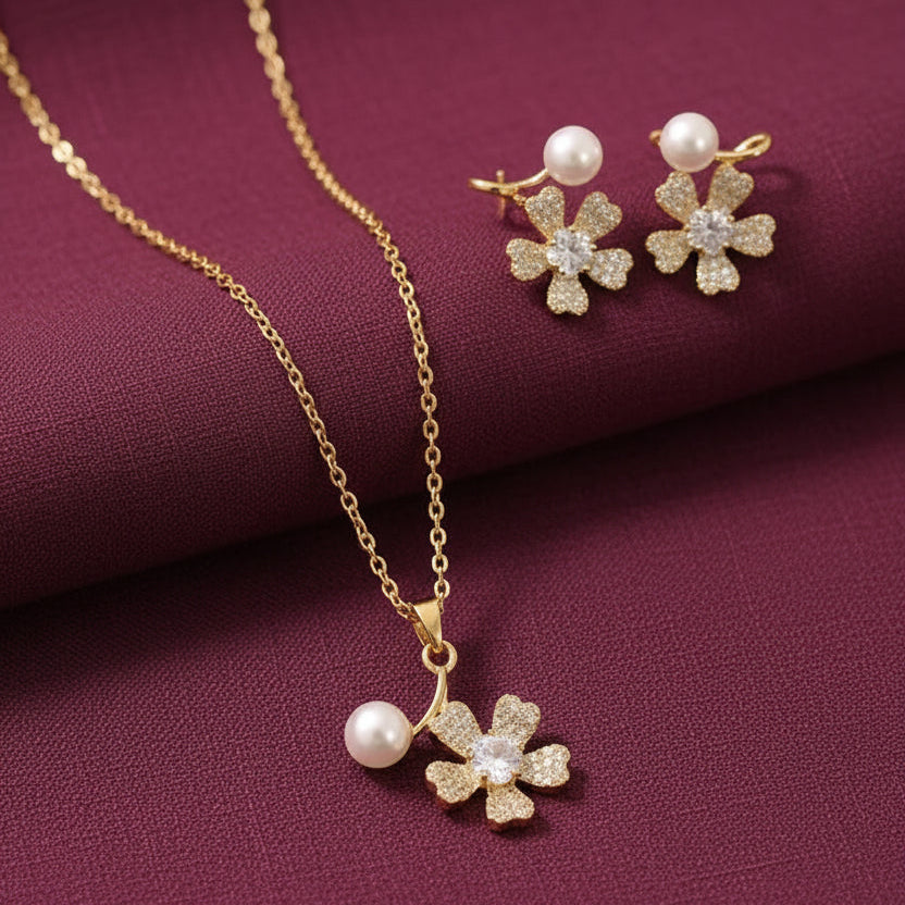 gold-tone floral pendant necklace and matching flower earrings with white pearl accents and sparkling crystal centres, displayed on burgundy satin by Evaj Jewels.