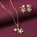 gold-tone floral pendant necklace and matching flower earrings with white pearl accents and sparkling crystal centres, displayed on burgundy satin by Evaj Jewels.