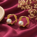 gold-tone geometric hexagon pearl stud earrings for women, featuring layered open-frame designs and elegant white pearl accents on burgundy satin by Evah Jewels.
