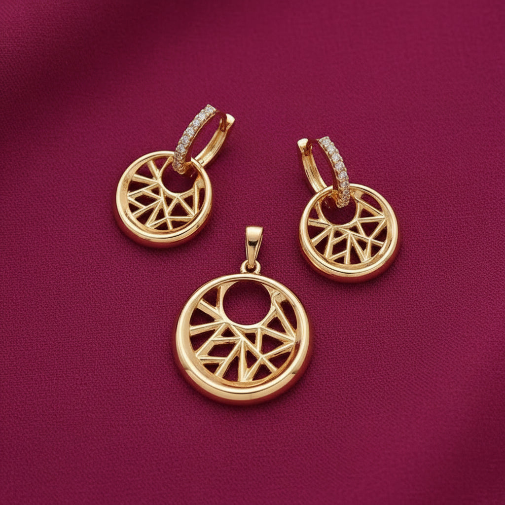 gold-tone geometric circular pendant and matching crystal-studded hoop drop earrings featuring an intricate openwork starburst design on burgundy fabric by Evah Jewels.