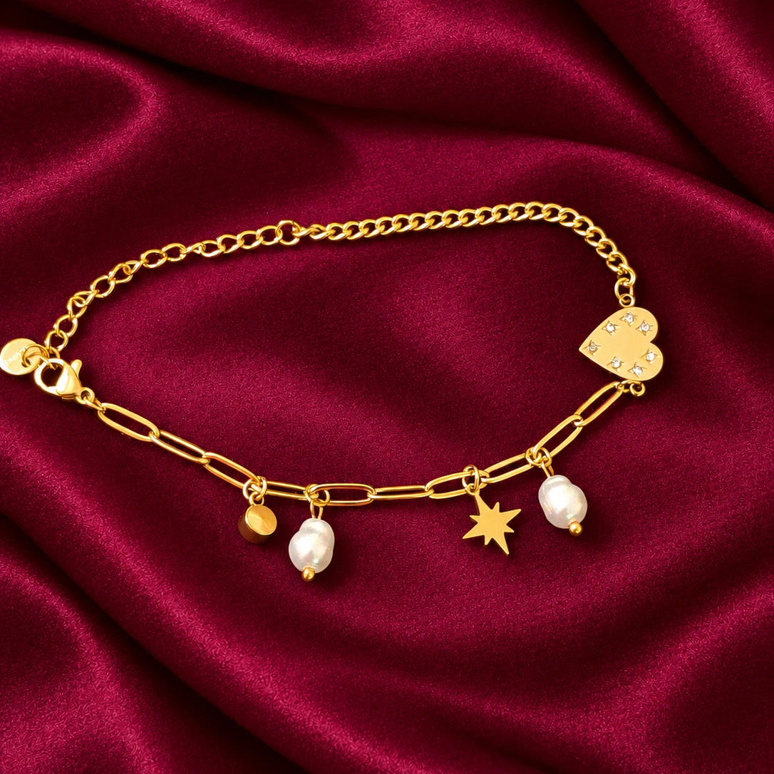 Discover effortless elegance with the EVAH JEWELS Gold Tone Heart and Pearl Charm Bracelet for Women, a beautifully designed fashion jewellery accessory featuring a delicate gold-tone chain link design adorned with charming decorative elements. This stylish bracelet showcases a polished gold heart charm embellished with sparkling white stones, two elegant white pearl-style drops, a beautiful star charm and a small round gold-tone charm. The combination of modern chain links, feminine pearl detailing and pla