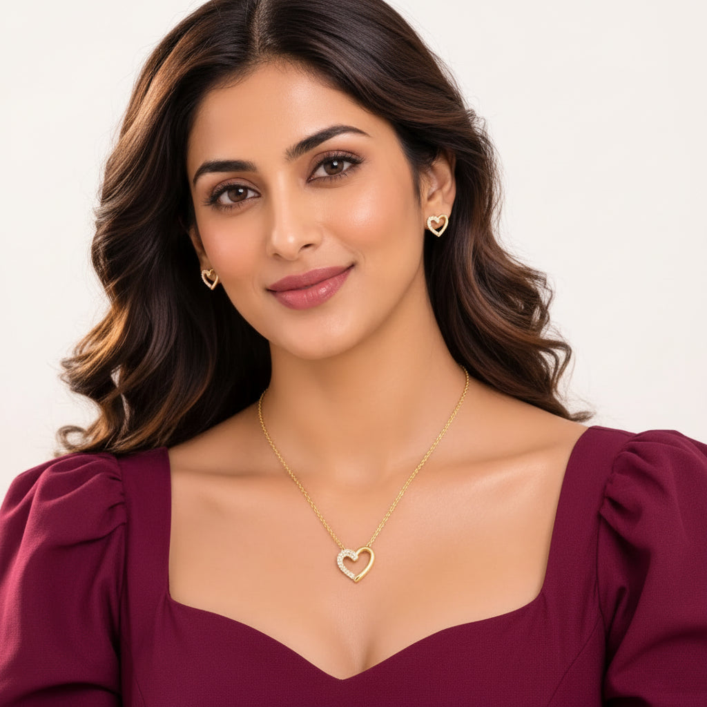 Model wearing EVAH JEWELS gold-tone open-heart pendant necklace and matching crystal-accented heart stud earrings with a burgundy dress, showcasing elegant fashion jewellery for women