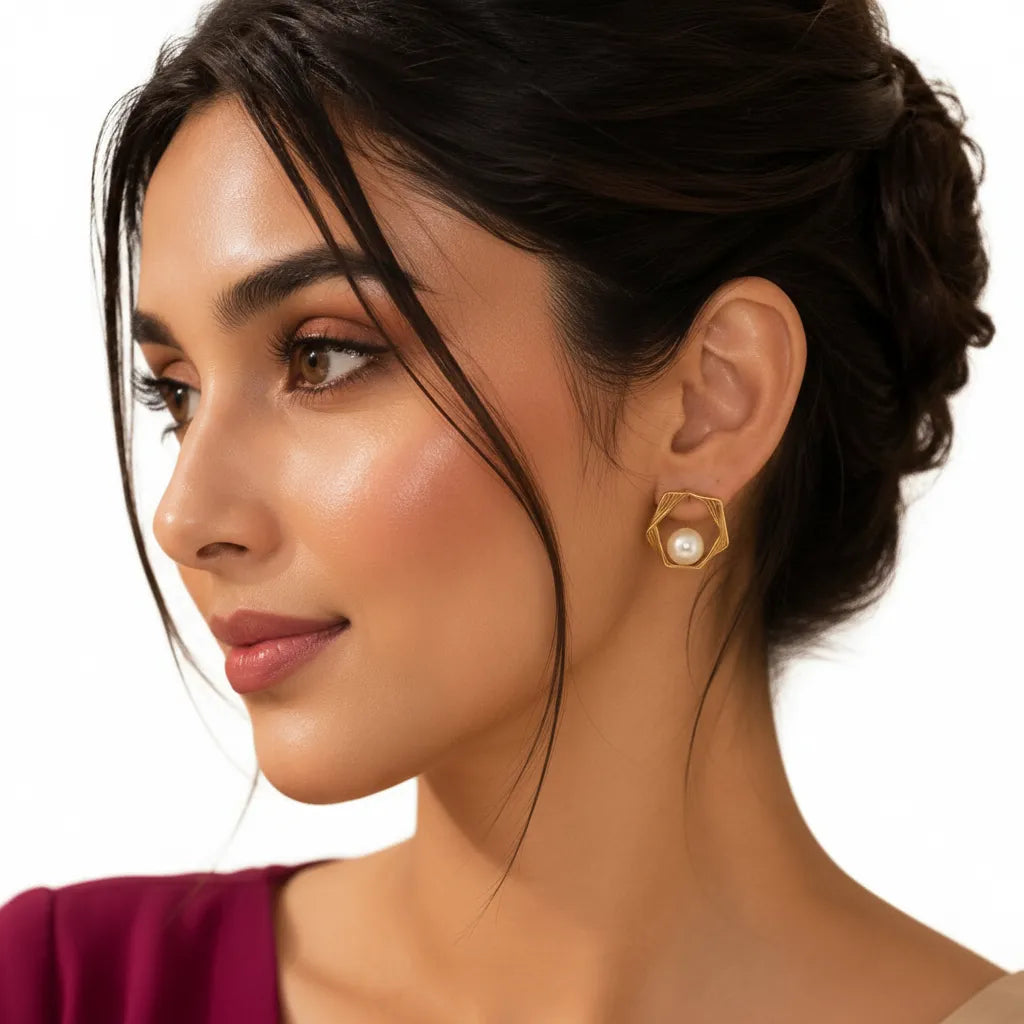 Woman wearing EVAH JEWELS gold-tone geometric hexagon pearl stud earrings with layered open-frame design and elegant white pearl accents, styled with a burgundy outfit.