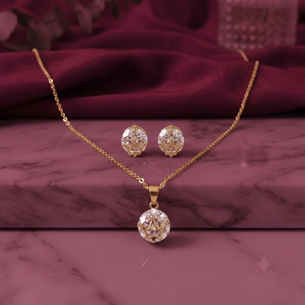 gold-tone oval crystal pendant necklace with matching sparkling stud earrings, featuring an elegant geometric design, displayed on a pink marble surface by Evah Jewels.