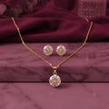 gold-tone oval crystal pendant necklace with matching sparkling stud earrings, featuring an elegant geometric design, displayed on a pink marble surface by Evah Jewels.