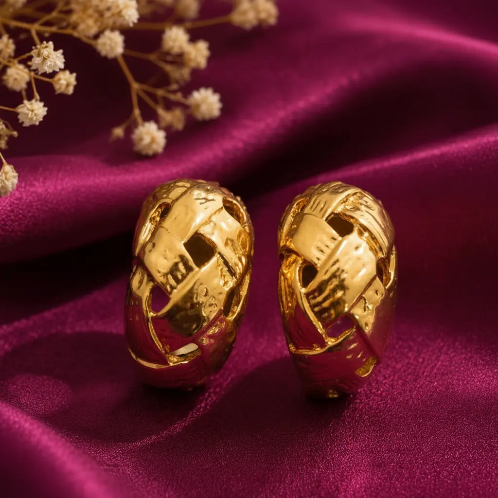 gold-tone chunky woven hoop earrings for women featuring an intricate interlocking braided design, textured polished finish and bold sculptural styling, displayed on luxurious burgundy satin fabric by Evah Jewels.