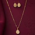 gold-tone teardrop pendant necklace and matching stud earrings set for women, featuring sparkling crystal-like stones and geometric star designs on a burgundy background by Evah Jewels.