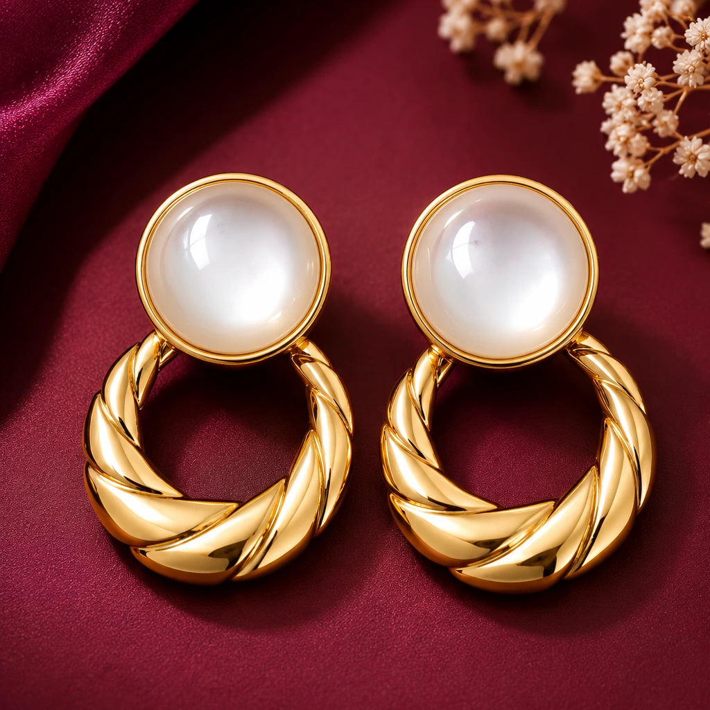 old-tone pearl twisted hoop drop earrings for women featuring glossy round white pearl-like studs and bold textured gold circular drops, displayed on luxurious burgundy fabric by Evah Jewels.